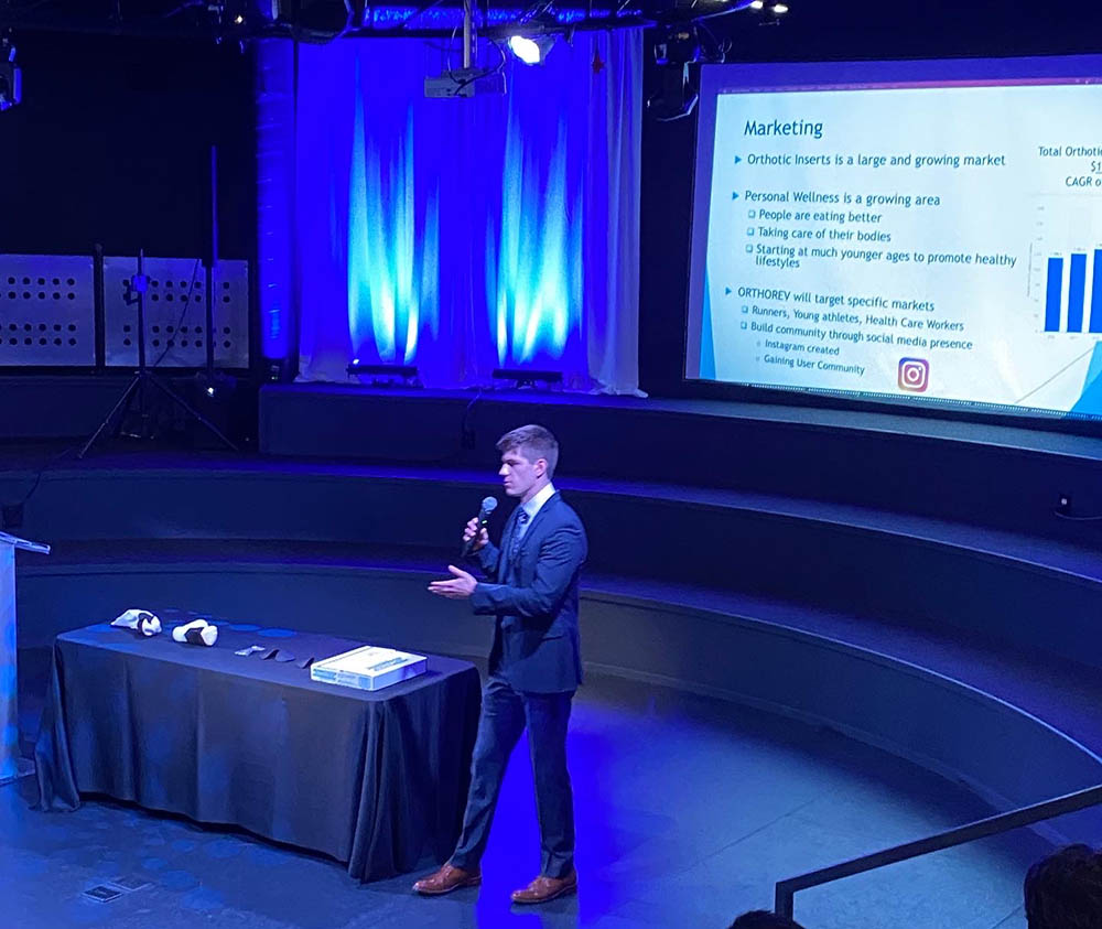 Benjamin Zawacki '22 stands in front of an audience delivering his presentation.