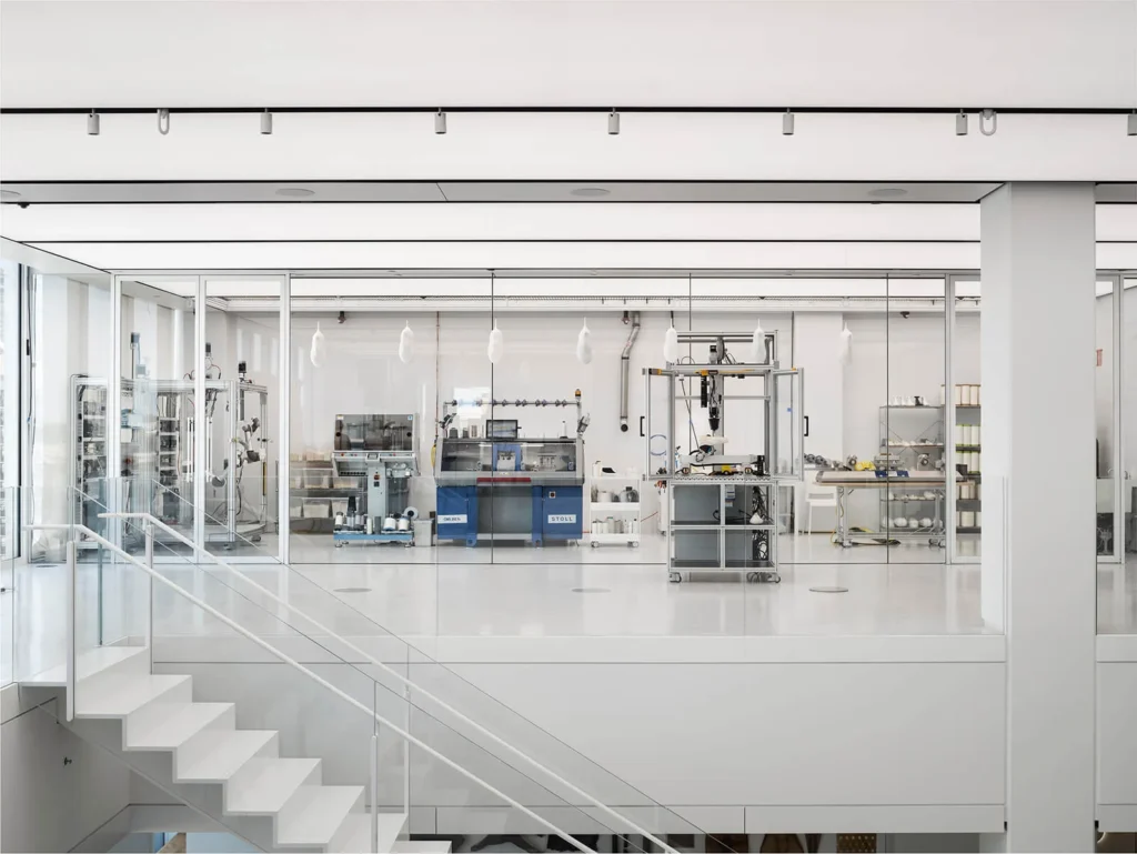 The robotic cell in the OXMAN Lab features a non-planar robotic 3D printing system, a high-fidelity melt blowing unit, a 3D knitting machine and a melt spinning fibre extrusion and conditioning line