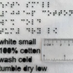 Izabela Ciesielska-Wrobel, assistant professor of textiles, fashion merchandising and design in URI’s College of Business, showing the size of the braille symbols compared to regular washing instructions. (URI photo/Izabela Ciesielska-Wrobel)