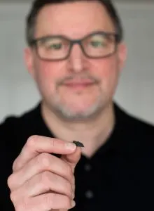Cristian Boffo holds a folded superconductor foil 3D printed from a single crystal of yttrium barium copper oxide. Credit: Melanie Turenne