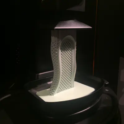 Carbon Digital Light Synthesis printer pulling a 3D‑printed midsole from a vat of liquid resin.