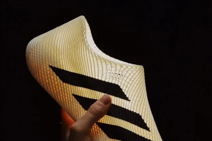 Hand holding Adidas’ fully 3D-printed Climacool sneaker, showing its seamless lattice design