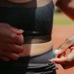 Close-up of Faith Kipyegon adjusting the Nike FlyWeb bra, highlighting open TPU mesh texture.