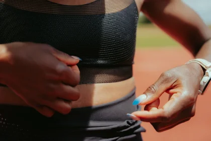 Close-up of Faith Kipyegon adjusting the Nike FlyWeb bra, highlighting open TPU mesh texture.