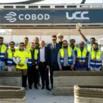 Construction crew standing beside a COBOD BODXL printer after a test print on the Doha school site