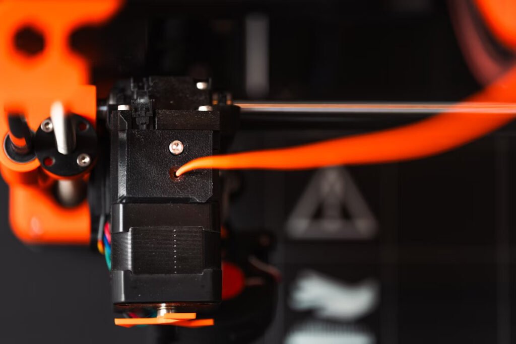 Close-up of an FDM printer nozzle extruding filament.
