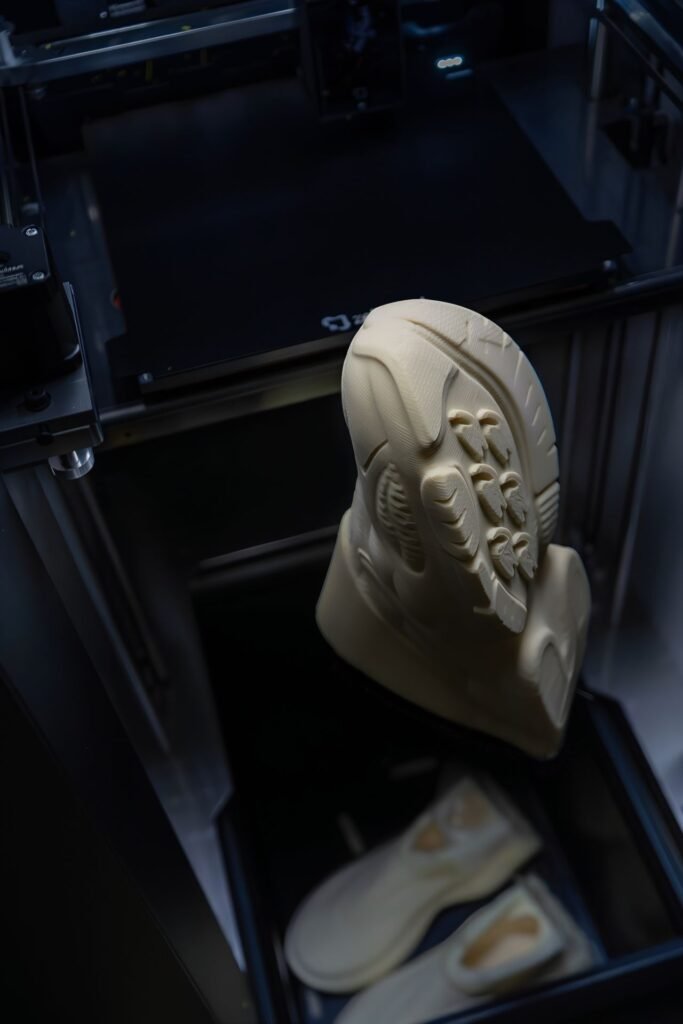 Beige 3D-printed shoe emerging from a Zellerfeld GEN3 printer chamber