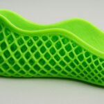 A bright green 3D-printed lattice shoe showing its mesh structure and smooth upper design.