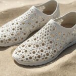 3D printed lattice shoes with sand trapped inside the open holes on a beach surface