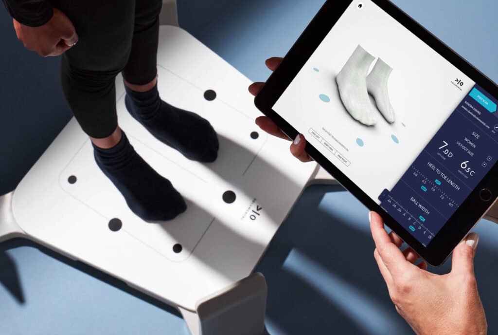 Customer standing on a Volumental foot scanner while a tablet displays 3D foot measurements.