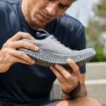 Person inspecting a 3D printed lattice shoe outdoors to check the TPU midsole for wear and durability.